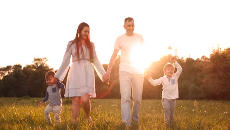 Happy-family-their-man-with-two-children-walking-on-the-field-at-sunset-in-the-sunset-light-in-the-summer-in-warm-weather.
